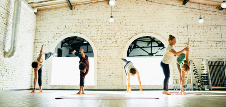 4 people doing yoga being supported by an instructor