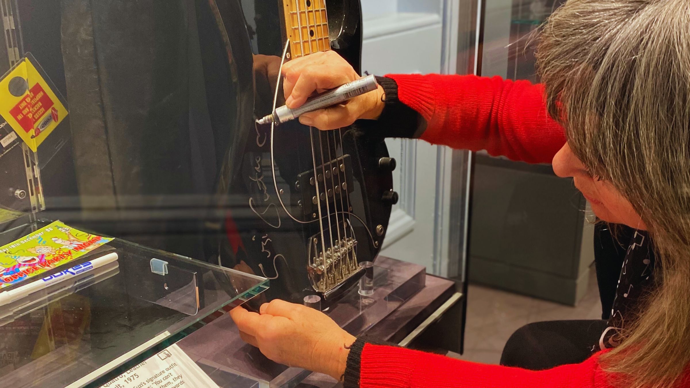 Suzi Quatro signing a black five-string bass guitar