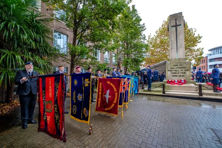 Multiple flags being held outwards in front of war memorial