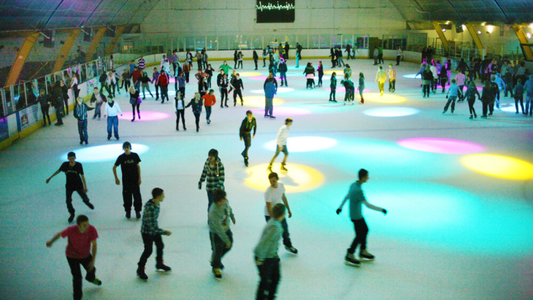 Ice rink being used by public with pink yellow blue lights