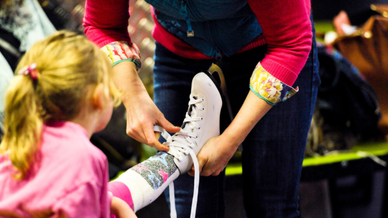 Girl being helped into ice skating shoe