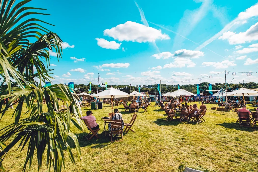 People Sit At Tables On A Sunny Day In The Creamfields Hospitality Area. Copyright Jack Kimber Photography