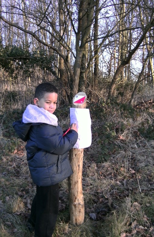 A child stands by an orienteering post