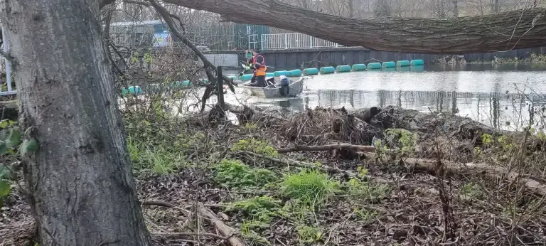 Wide shot of boat pulling litter from the river