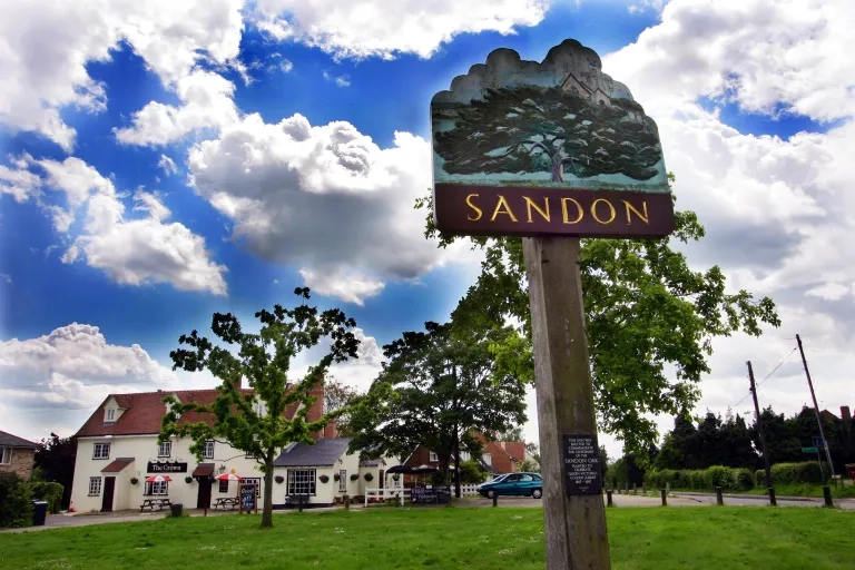 Village sign for Sandon with pub in background