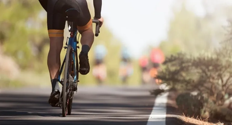 A Cyclist's Legs And Bike Are Seen Following Behind Four Cyclists Out Of Focus A Few Metres Ahead