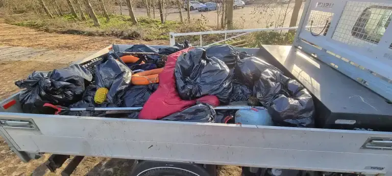 Back of truck full of black bin sacks