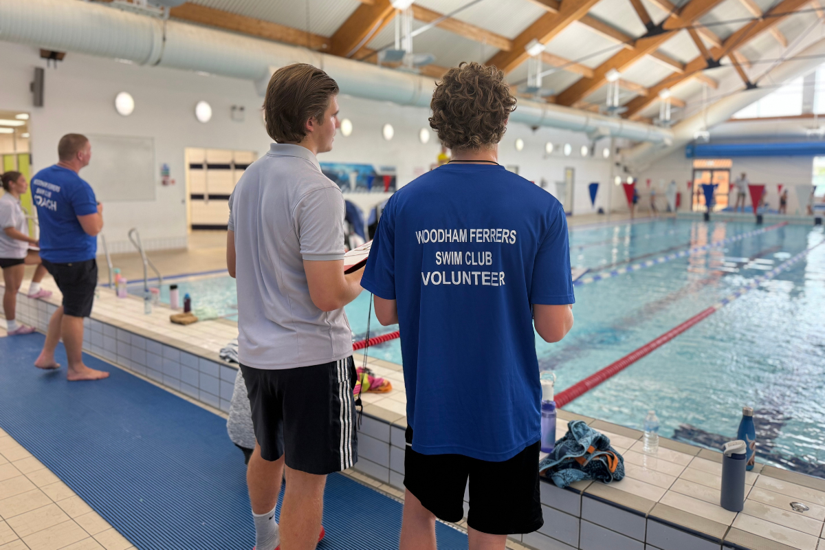 Swim school teachers and club coaches observe a race at the gala.png