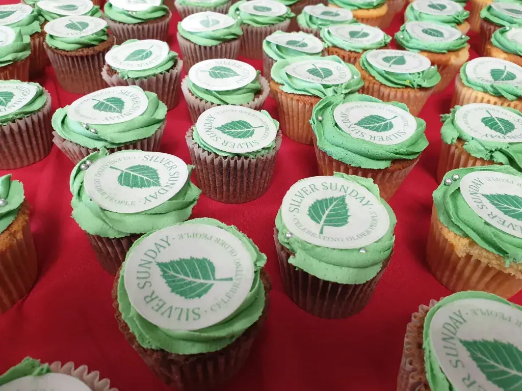 Cupcakes With The Silver Sunday Logo On Top Of Green Icing