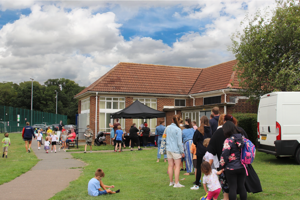 Children And Adults Queue For Lunch At Picnic In The Park