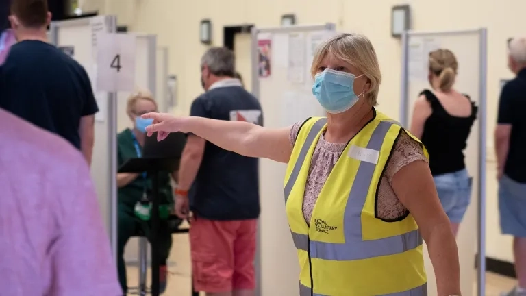 Person in high-vis directing people to get vaccinated