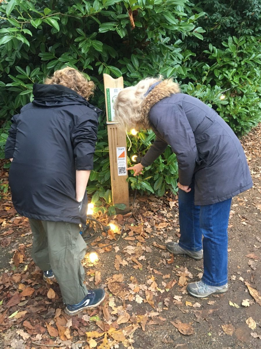 Two people investigate an orienteering marker at Hylands