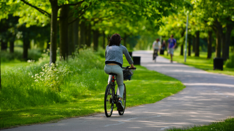 A Woman Cycles Through A Park On A Sunny Day. (Credit Nick Strugnell)