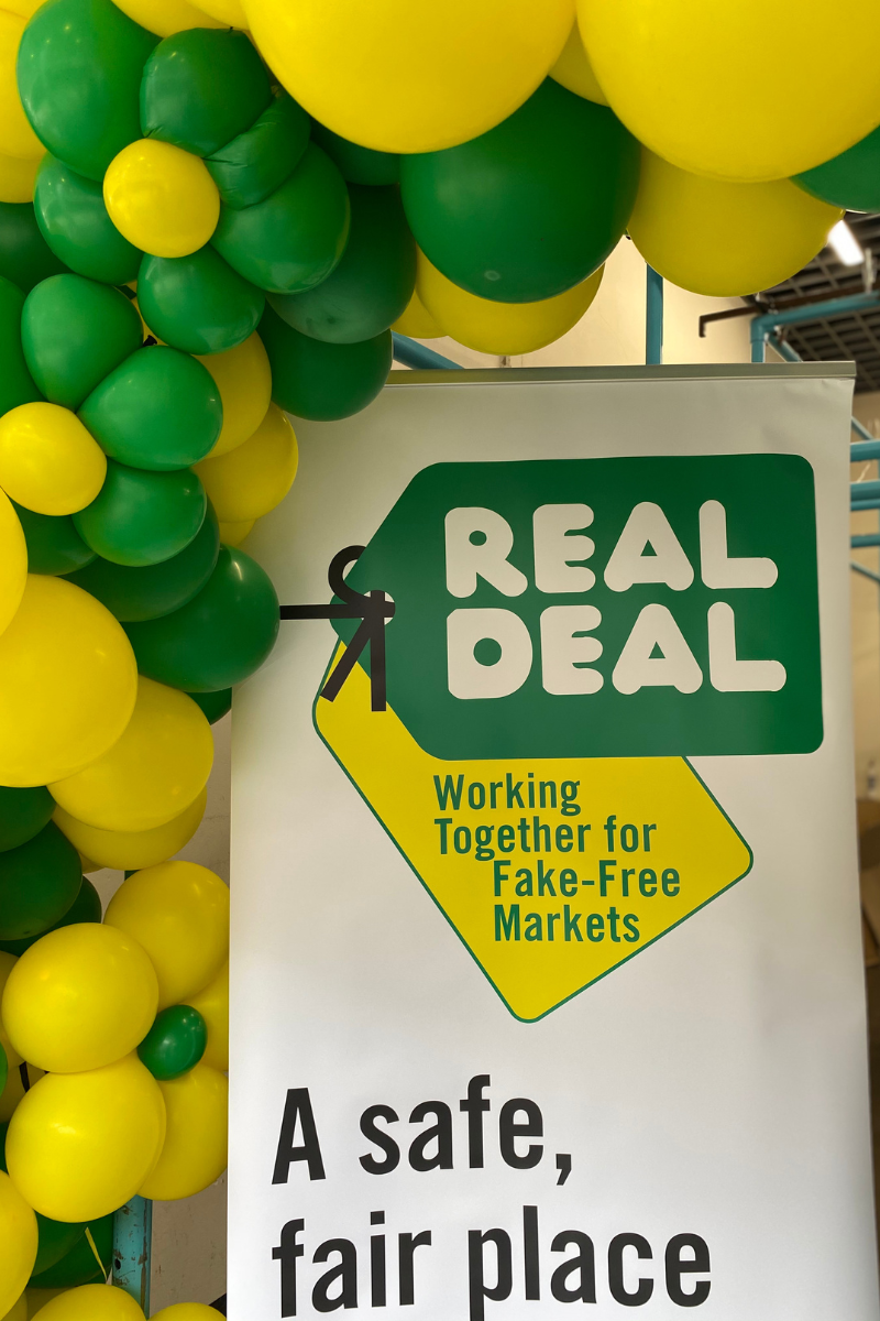Real Deal Logo Displayed Under A Greeen And Yellow Flower Balloon Arch
