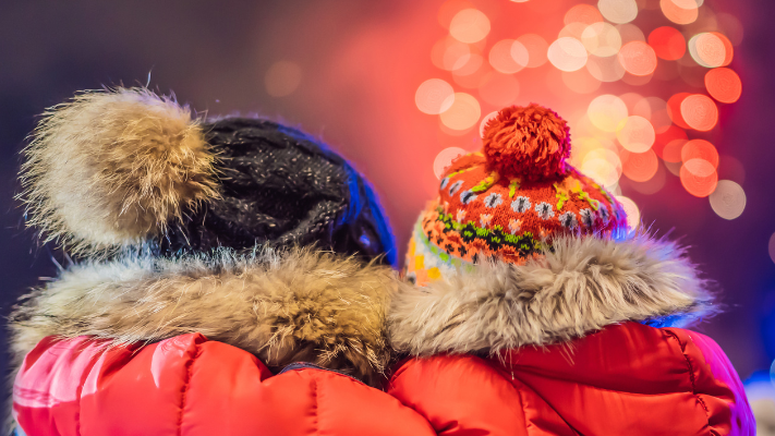 An Adult A Child Wearing Bobble Hats Look Out At Fireworks